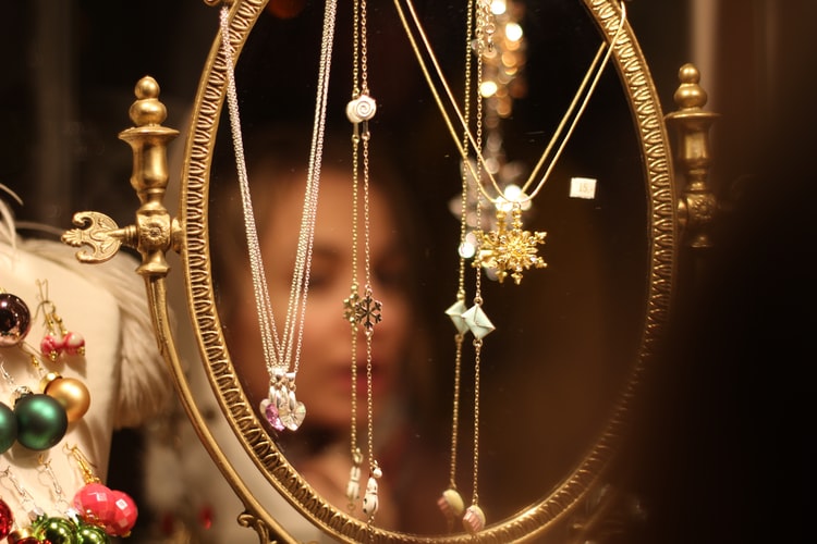 Couple exchanging a small wrapped jewelry box, minimalist gold necklace visible on a nearby dresser