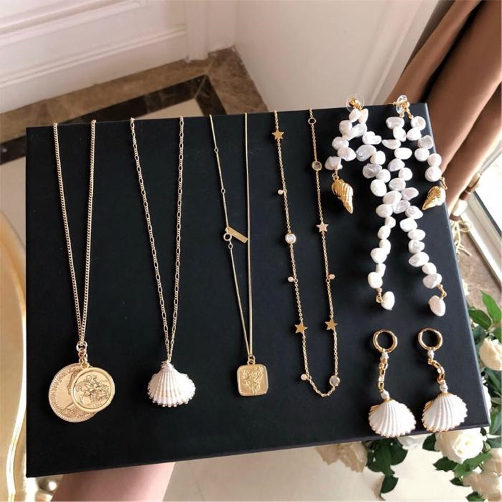 Flat lay of five curated gold jewelry pieces arranged neatly on a white background
