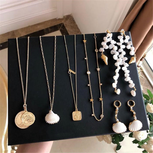 Flat lay of five curated gold jewelry pieces arranged neatly on a white background