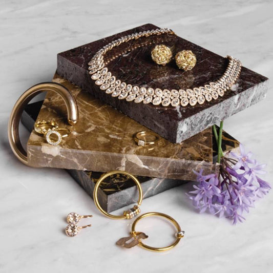Woman opening a small gift box with delicate gold stud earrings inside, casual home setting
