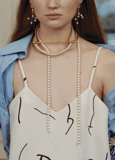 Woman wearing a layered gold necklace set, celebratory dinner table in background