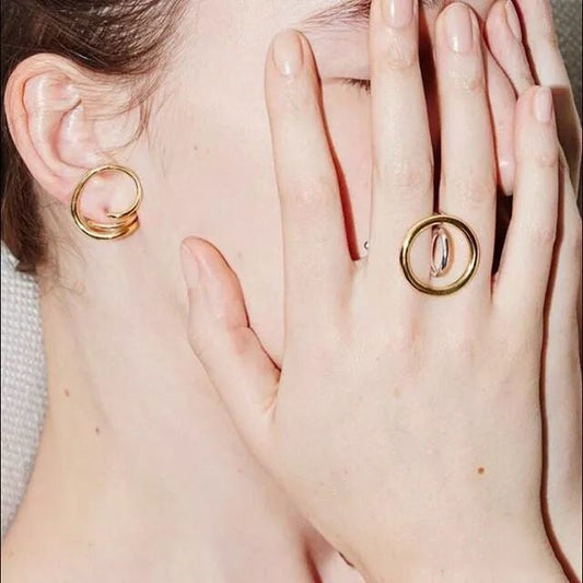 Woman casually wearing gold hoop earrings while making coffee at home, ordinary weekday morning